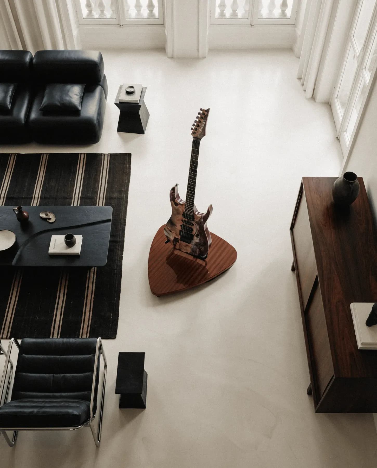 Overhead view of a minimal living room with an electric guitar standing on a wooden pick-shaped stand