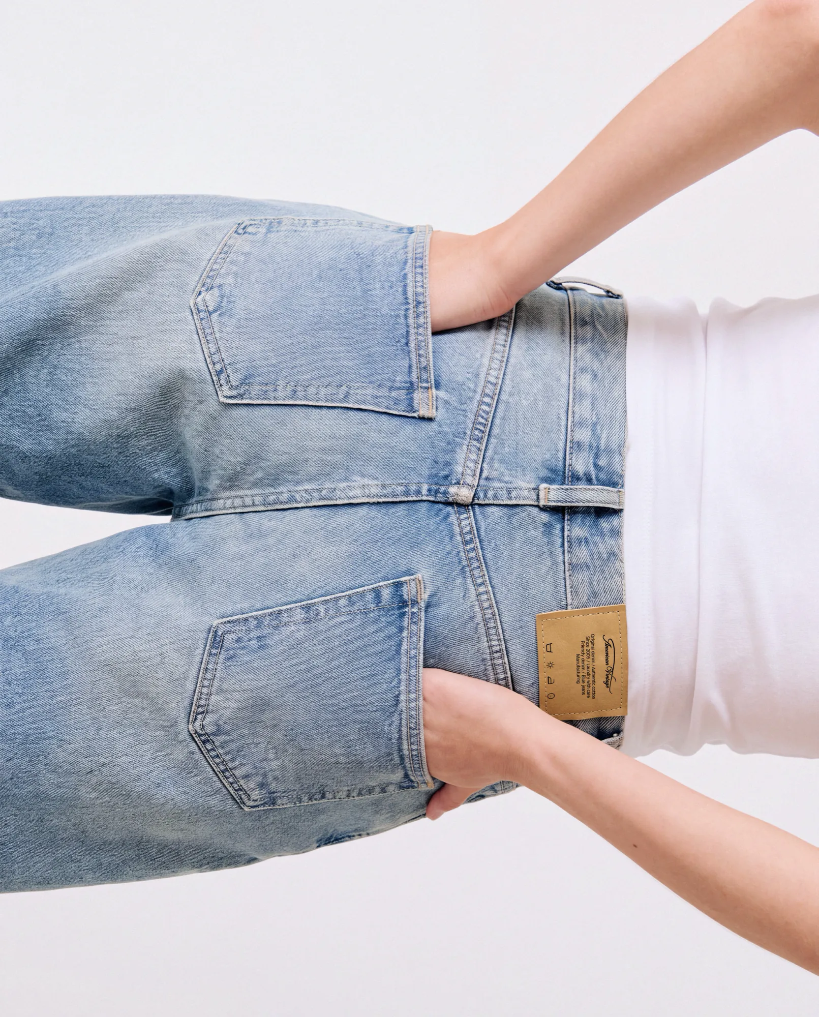 Hands slipped into the back pockets of light-wash jeans