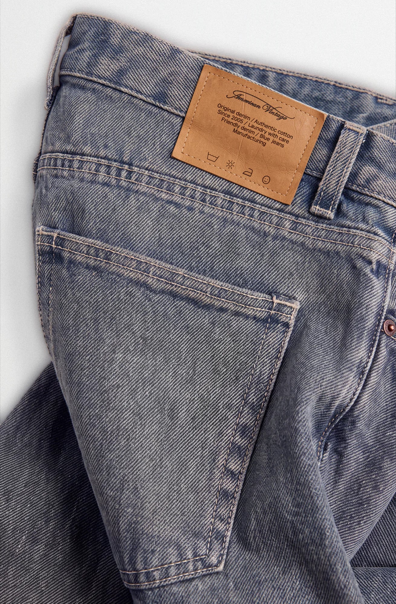Poche arrière et étiquette en cuir d’un jean délavé gris