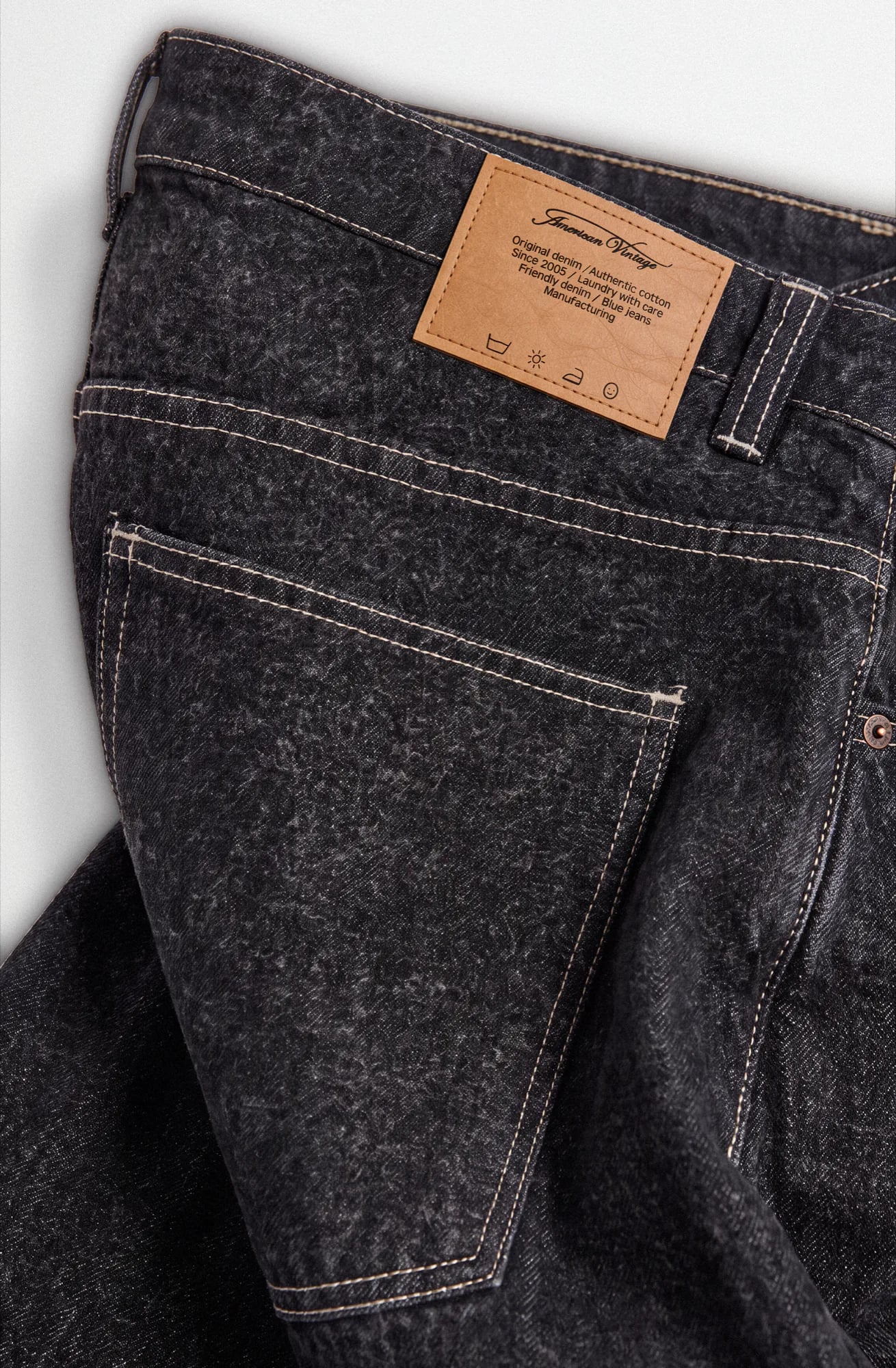 Back pocket and leather patch of washed black jeans