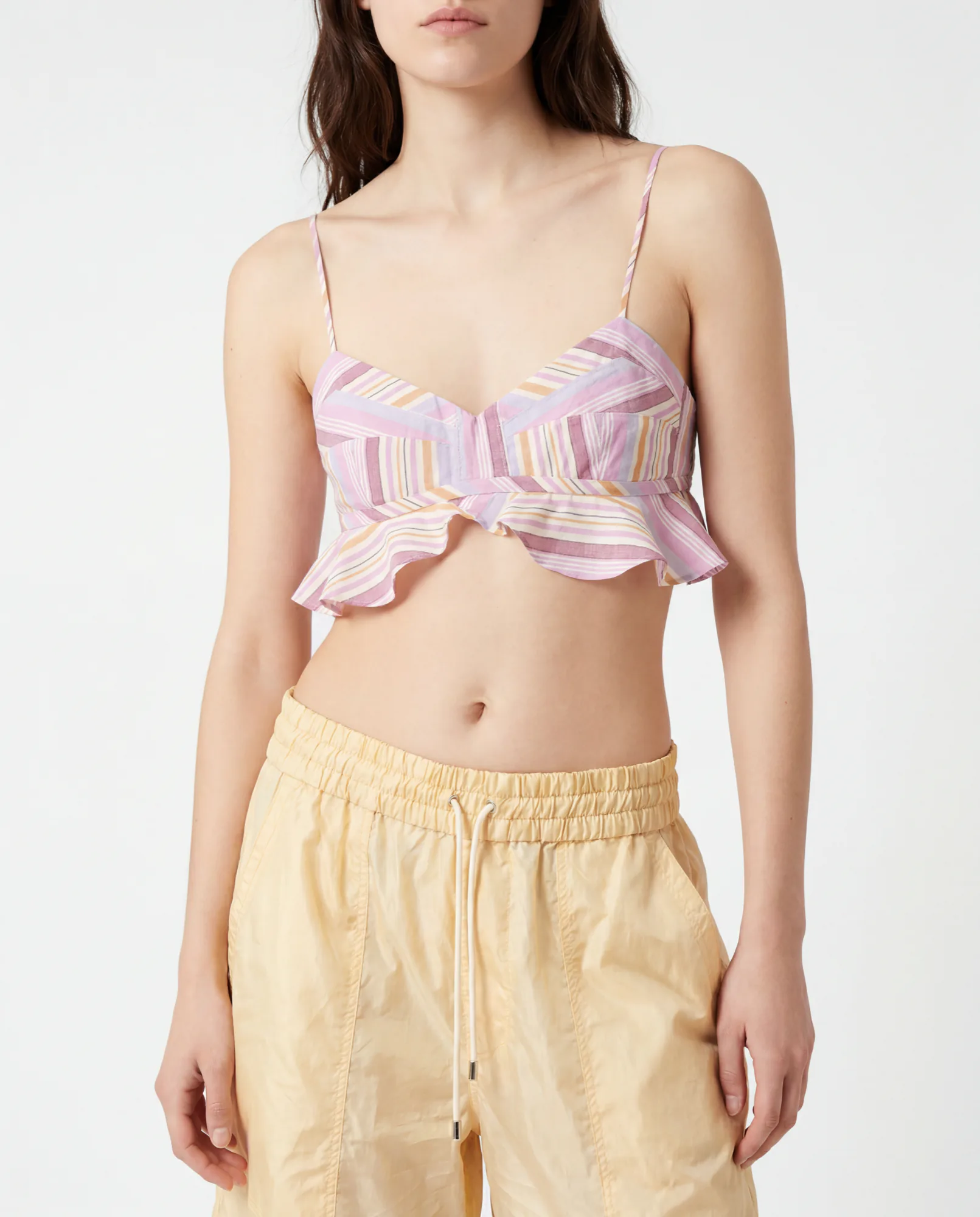 Model in a pink ruffled bra top and pale yellow drawstring trousers
