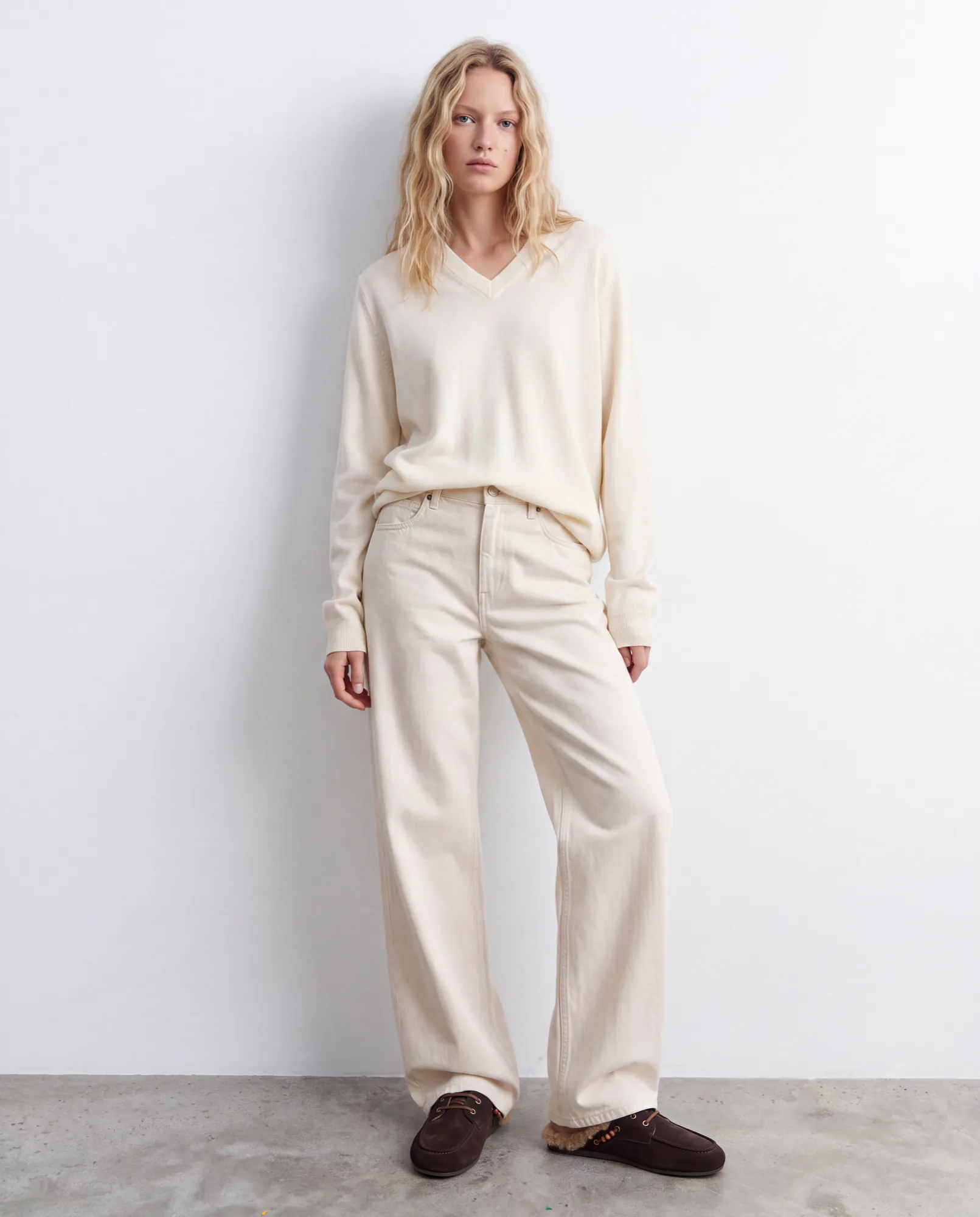 Model in a cream sweater and trousers with brown suede shoes