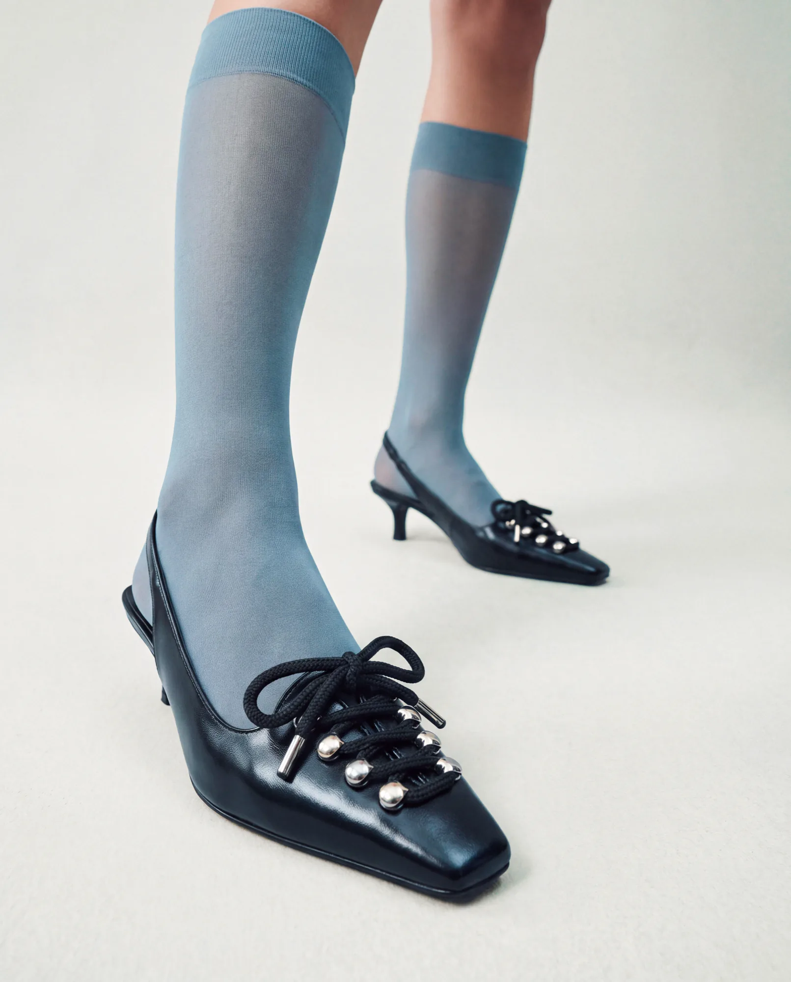 Black lace-up kitten heels worn with sheer blue socks