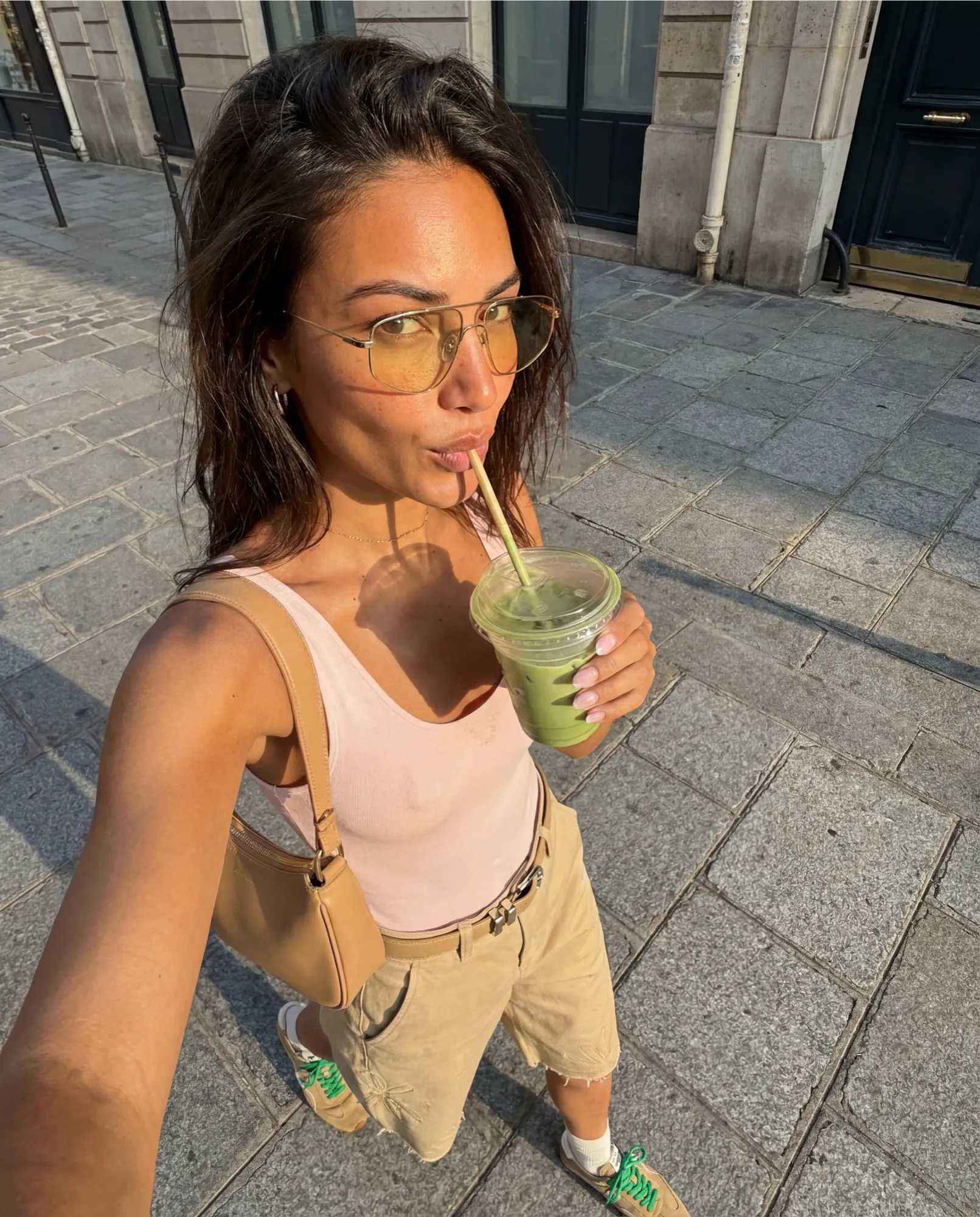 Selfie d’une femme en lunettes de soleil buvant un matcha glacé, style UGC