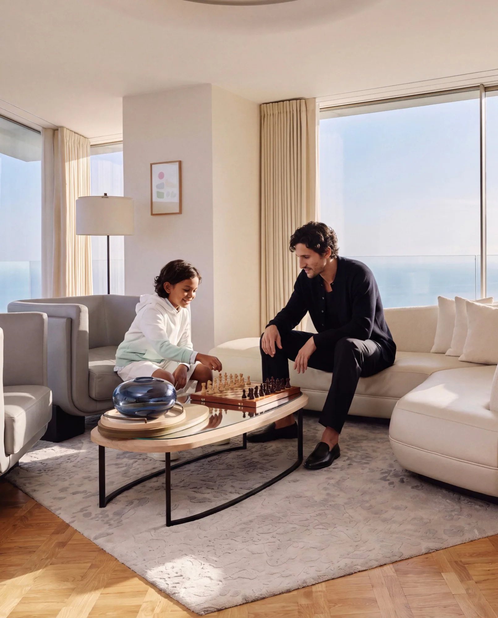 Two guests playing chess in a bright hotel suite overlooking the sea