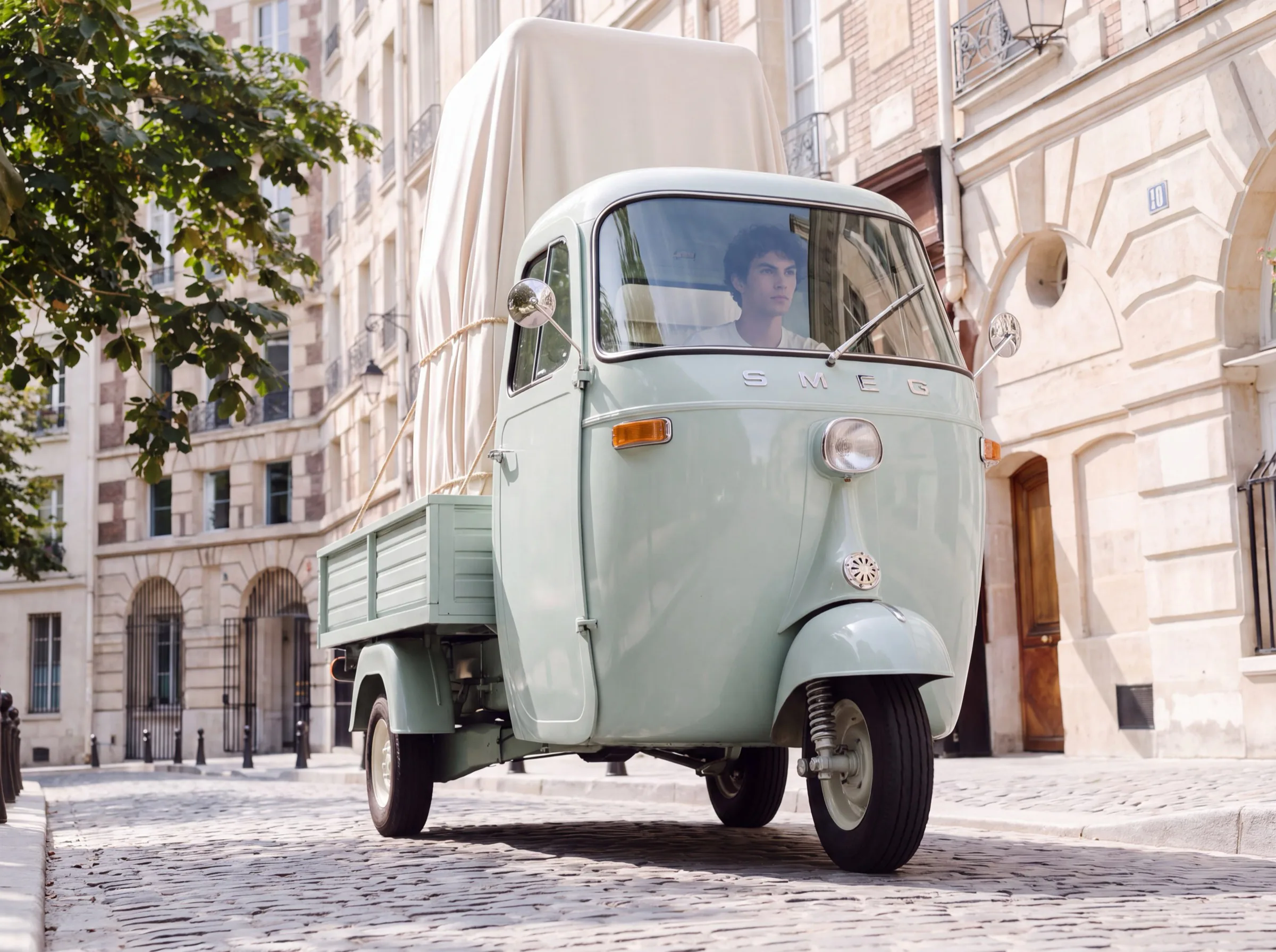 Pale green Smeg three-wheeler van parked on a Paris cobbled street